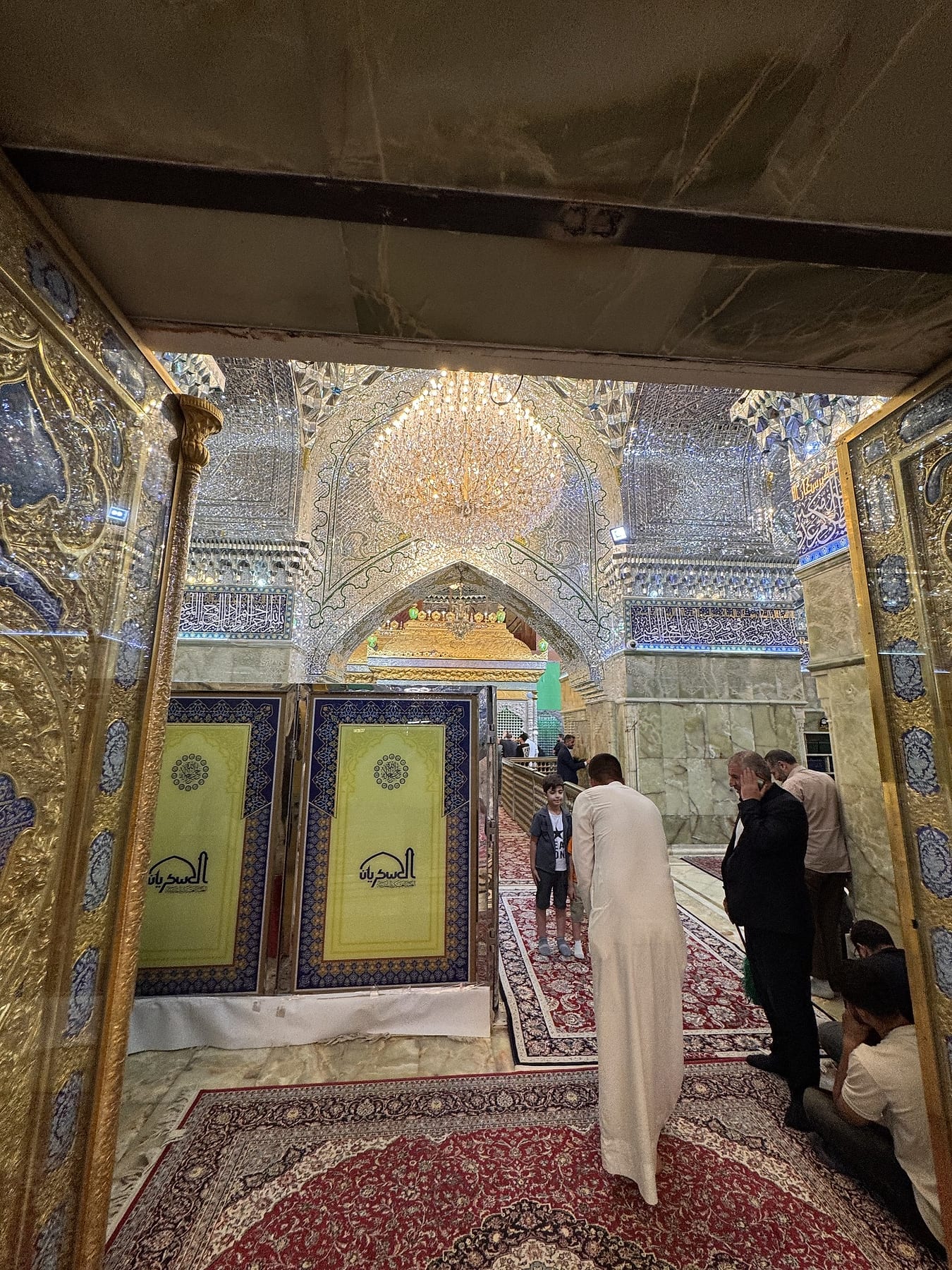 A mirrored hall with tiled panels and a red carpet runner, with visitors walking through